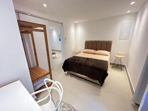 1 dormitorio con 1 cama, 2 mesas y espejo en Lançamento,Duas suítes Leblon,segunda quadra da praia, en Río de Janeiro