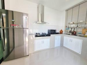 a kitchen with a stainless steel refrigerator and white cabinets at Kgrandville house-siri 