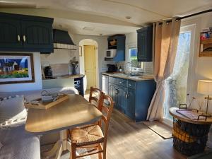 cocina con armarios azules, mesa y sillas en Red Tub Cabin Snowdonia, en Llanrwst