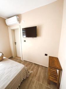 1 dormitorio con 1 cama y TV de pantalla plana en la pared en GÖKÇEADA BADEMİ BUTİK OTEL en Gokceada Town