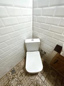 baño con azulejos blancos y aseo blanco en GÖKÇEADA BADEMİ BUTİK OTEL en Gokceada Town