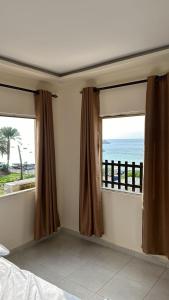 een slaapkamer met 2 ramen met uitzicht op de oceaan bij PALM BEACH HOTEL free ticket for pedal boat تذكرة مجانية للالعاب البحرية in Aqaba