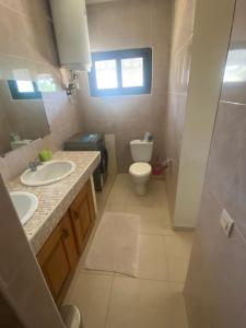 baño con 2 lavabos, aseo y ventana en Amina Haus en Sali Poulang