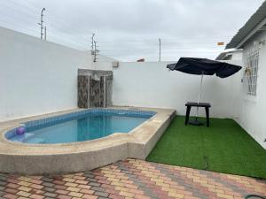 a swimming pool with an umbrella next to a house at CaSa PrivaDa con Piscina in Playas