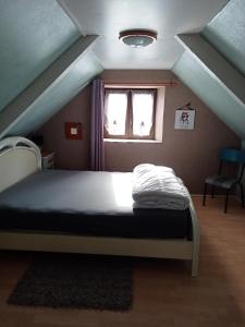 1 dormitorio con 1 cama en un ático con ventana en Gîte du Kreizker, en Cléden-Poher