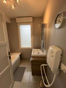 łazienka z toaletą, umywalką i zegarem w obiekcie La maison du bonheur 70 m² w mieście Saint-Amand-les-Eaux