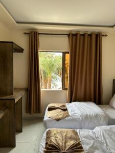 una camera d'albergo con due letti e una finestra di PALM BEACH HOTEL free ticket for pedal boat تذكرة مجانية للالعاب البحرية ad Aqaba