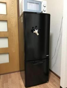 a black refrigerator with a toy cow on the door at ZY House in Osaka