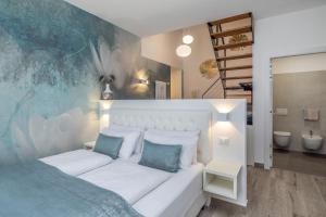 ein Schlafzimmer mit einem weißen Bett mit blauen Kissen in der Unterkunft Maison Valentina in Meran