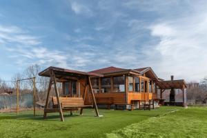 a wooden house with a swing and a playground at Елата in Zasele