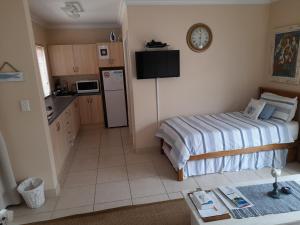 a small kitchen with a bed and a refrigerator at Barnard Self Catering Apartments in St Francis Bay