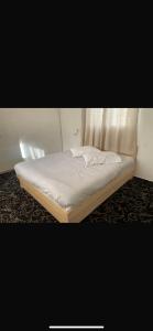 a bed in a room with a white mattress at EVAN PARK in Buq‘ātā