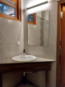 La salle de bains est pourvue d'un lavabo blanc et d'un miroir. dans l'établissement Orchid Dream, à Bentota