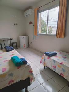 Pokój z 2 łóżkami, oknem i stołem w obiekcie Aquarela Suítes w mieście Piúma