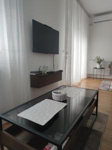 een woonkamer met een glazen tafel en een televisie bij Apartman 022 in Smederevska Palanka