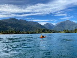 a person in a kayak on a lake with mountains at Puerta austral in Puelo
