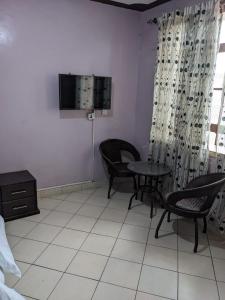 a room with a table and chairs and a tv at Madola Hotel in Nairobi