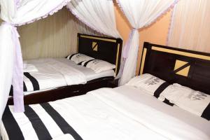 two beds in a bedroom with curtains andskirtsomaly at Madola Hotel in Nairobi