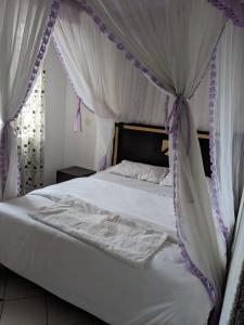 a bedroom with a bed with purple and white canopy at Madola Hotel in Nairobi