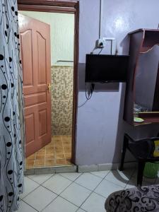 a bathroom with a door and a television in a room at Madola Hotel in Nairobi