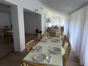 a dining room with a long table with plates and chairs at Pensiunea Marydor in Gârda de Sus