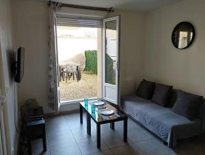 een woonkamer met een bank en een tafel bij Appartement 2, Jardin, collation, 5 min de l'aéroport CDG in Le Mesnil-Amelot
