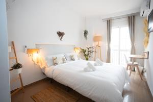 um quarto com uma grande cama branca com lençóis brancos em Naim Guest House Nerja em Nerja