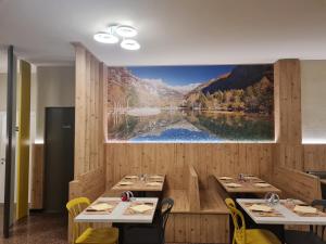 a restaurant with two tables and a large painting on the wall at Hotel ristorante Bucaneve in Val Masino