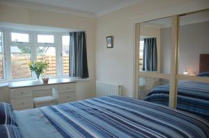 a bedroom with a bed and a desk and a mirror at Wulfrun in Tywyn