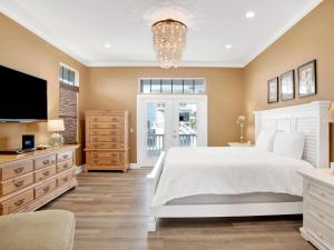 a bedroom with a white bed and a tv at Playa Panferio in Pensacola Beach
