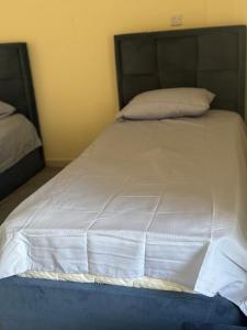 Una cama con sábanas blancas y almohadas. en provis, en Sharjah