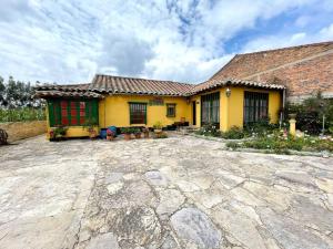 una casa amarilla con una entrada de piedra delante de ella en Great Rustic Colonial Villa in Punta Larga, Boyacá, en Nobsa