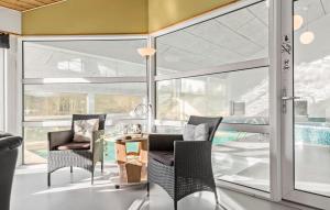 エーベルトフトにあるAwesome Home In Ebeltoft With 5 Bedrooms, Sauna And Wifiのガラスドア、テーブル、椅子が備わる客室です。