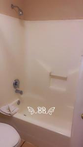 y baño con bañera blanca y aseo. en Days Inn & Suites by Wyndham Braunig Lake en Elmendorf