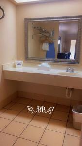 a bathroom with a sink and a mirror at Days Inn & Suites by Wyndham Braunig Lake in Elmendorf