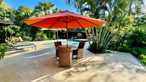 塔馬蘭的住宿－Villa Petit Tamarin : piscine bar et grand jardin tropical，游泳池旁遮阳伞下的桌椅