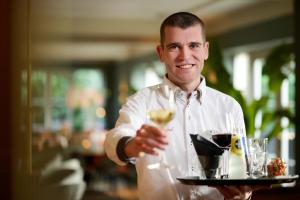 a man is holding a tray with a drink at Hotel 't Kruisselt in De Lutte