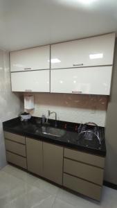 a kitchen with a sink and white cabinets at Apto São Pedro, pertinho UFJF in Juiz de Fora