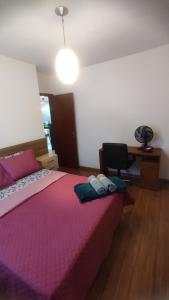 a bedroom with a bed with a pink blanket and a desk at Apto São Pedro, pertinho UFJF in Juiz de Fora