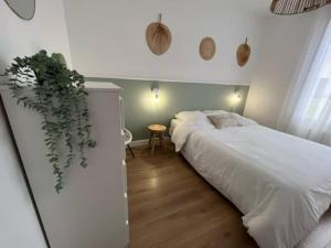 ein Schlafzimmer mit einem weißen Bett und einer Pflanze an der Wand in der Unterkunft Chez Marie-Jeanne 