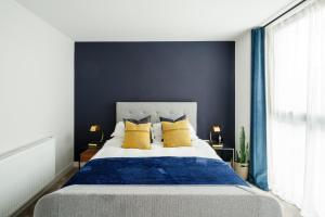 a bedroom with a bed with blue walls and yellow pillows at Beautiful & Contemporary Hackney Retreat in London