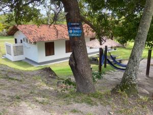 una casa con un cartel azul en un árbol en Chalés dos Carneiros, en Tamandaré