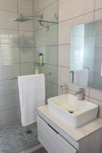 a white bathroom with a sink and a mirror at Hummingbird in Pretoria