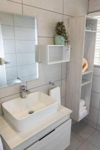 Baño blanco con lavabo y espejo en Hummingbird, en Pretoria