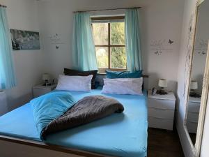 Schlafzimmer mit einem Bett mit blauer Bettwäsche und einem Fenster in der Unterkunft Ferienwohnung Breu in Arnbruck
