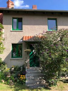 una casa con una puerta verde y algunas flores en Little Cottage auf 2 Etagen en Raben Steinfeld