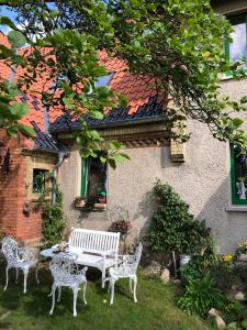 a white bench and chairs in front of a building at Little Cottage auf 2 Etagen in Raben Steinfeld