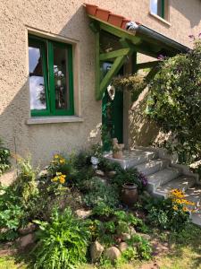 ein Haus mit grünem Fenster und ein paar Blumen in der Unterkunft Little Cottage auf 2 Etagen in Raben Steinfeld