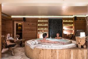 two people sitting in a hot tub in a room at Hôtel Alpen Ruitor in Méribel