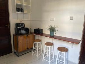 a kitchen with two stools and a counter with a microwave at Nashu House Stone Town in Ngambo